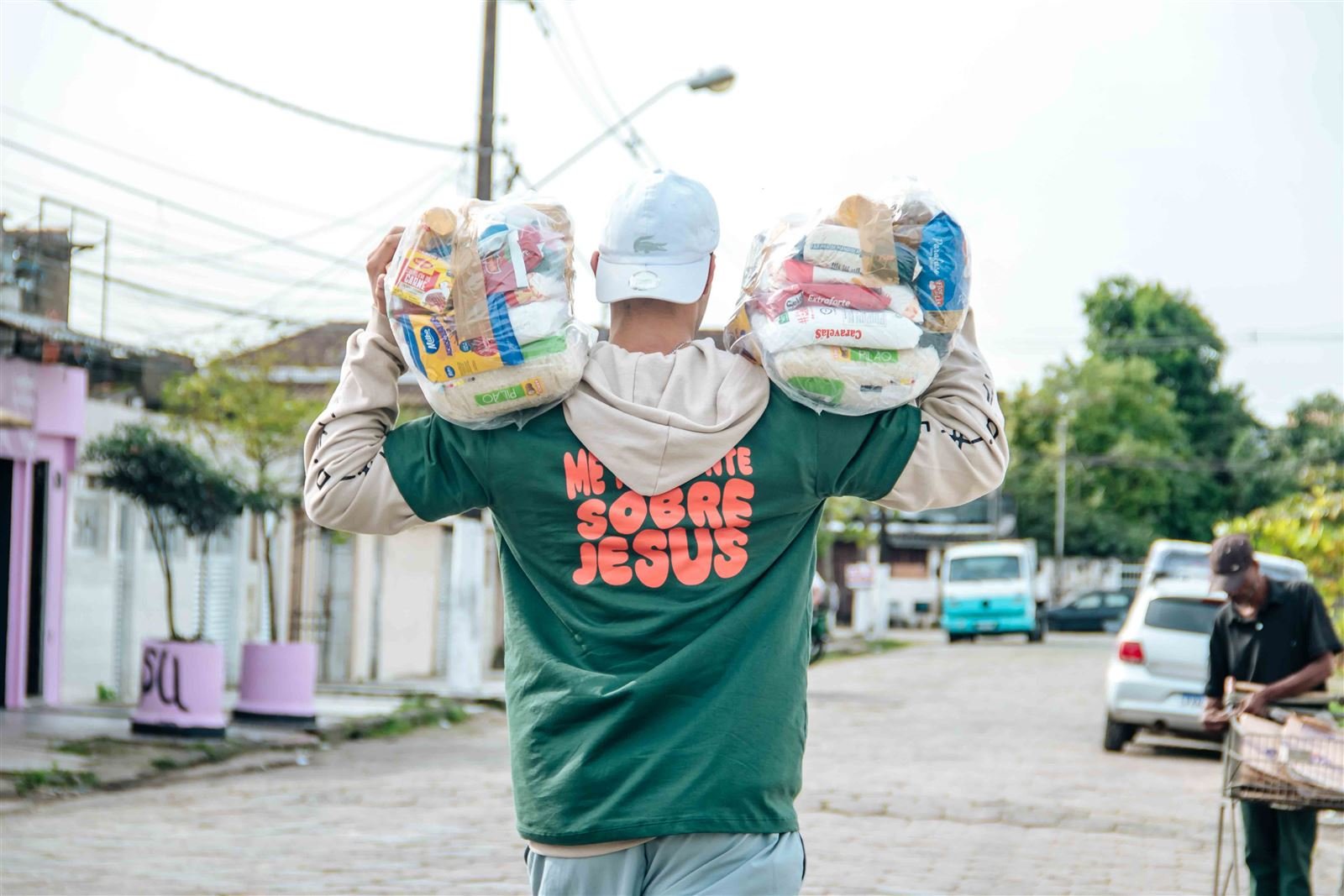 Voluntário carregando cestas básicas pela rua durante ação missionária